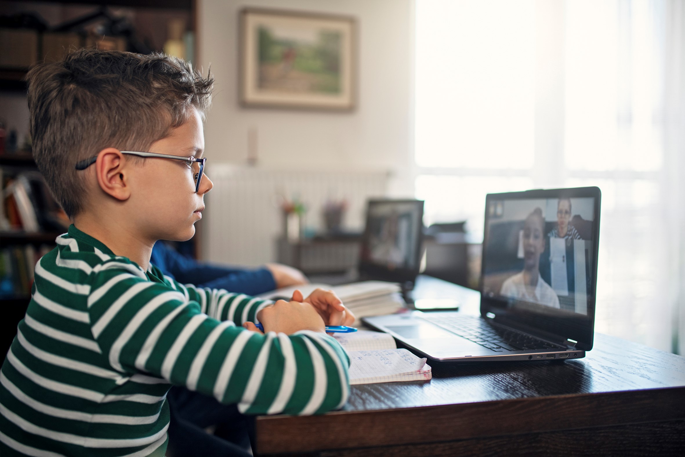 Little boys attending to online school class.